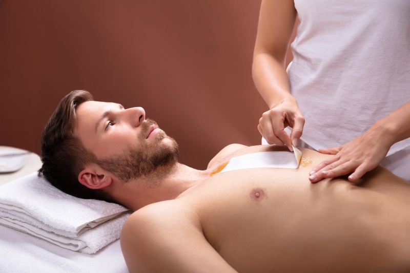 Male esthetician performing body waxing for men